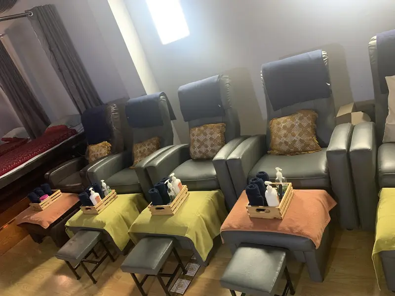 Row of grey recliner chairs with footrests and towels for foot massage