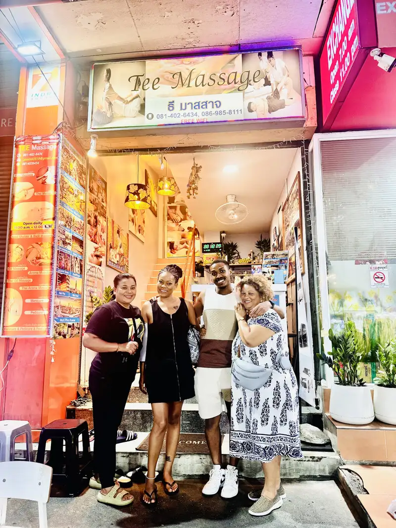 Guests posing at the street entrance of Tee Massage, with the service banner on the left
